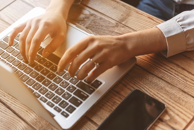 Close up of woman typing on laptop in coffee shop