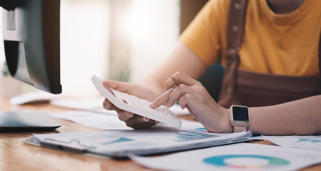 Close up woman using calculator and laptop for do math finance on wooden desk in office and business working background, tax, accounting, statistics and analytic research concept