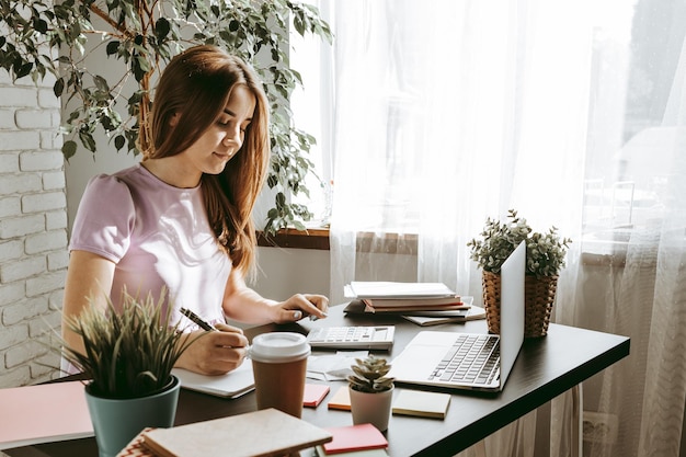 Close up of a woman writing something on the paper in office