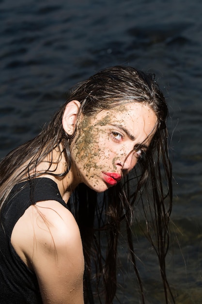 A close up of a womans face covered in mud