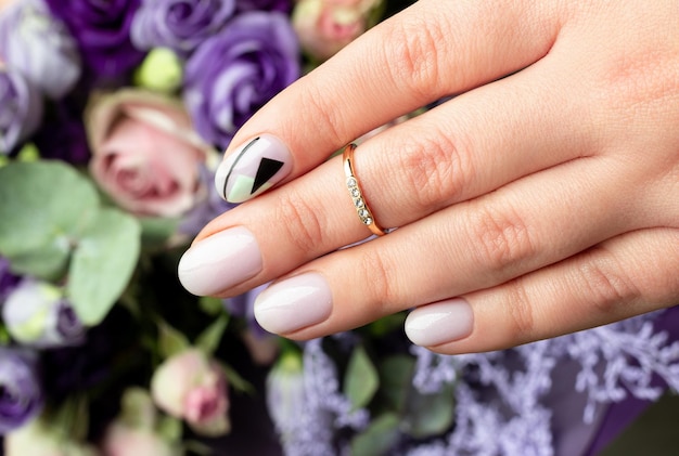 Close up womans hand with creative nail design on flower background