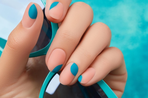 Close up womans hand with summer manicure on blue background manicure design trends