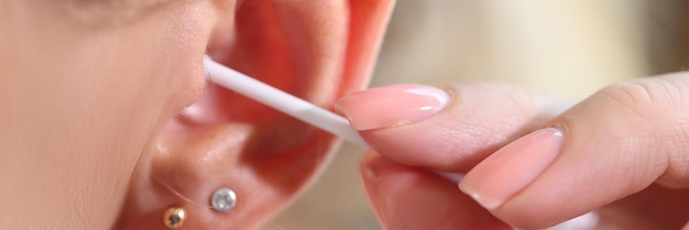 Close up of women cleans her ear with cotton swab Hygiene of people and body care concept