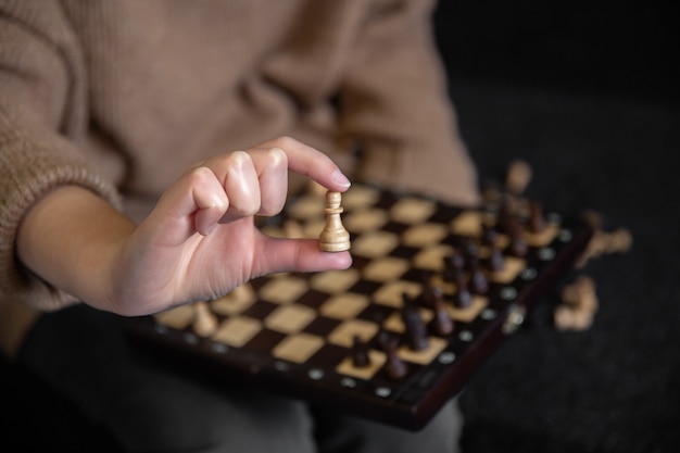 Close up of wooden chess piece in female hands, blurred background.