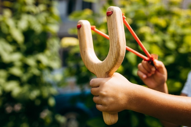 Close up wooden slingshot toy in hands of little girl