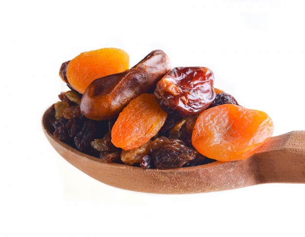 Close up on wooden spoon with dates and dried fruits isolated