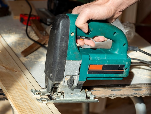 Close-up of a worker sawing a wooden Board with an electric jigsaw