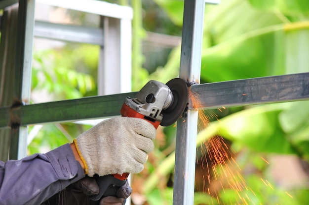 Close up worker using angle grinder polishing steel structure with yellow sparks