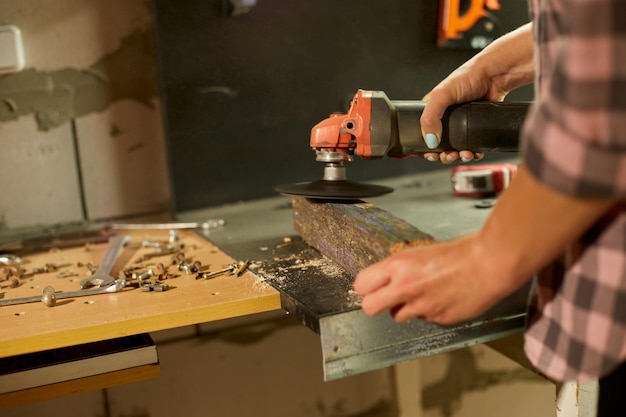 Close up of a worker woman hand grinds sanding the wood in workshop