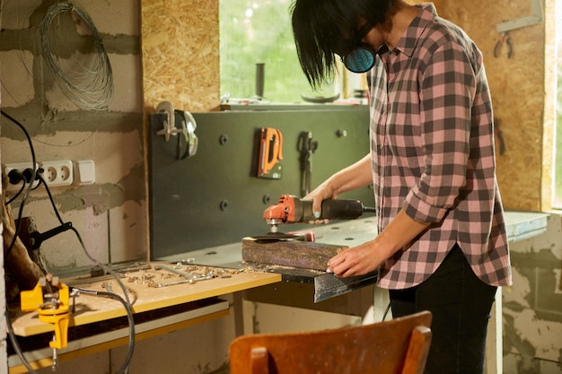 Close up of a worker woman hand grinds sanding the wood in workshop