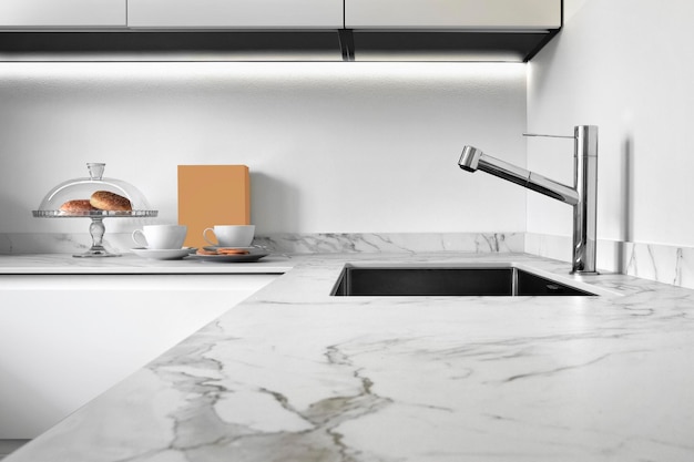 Close up of a worktop of a modern kitchen in the foreground the steel sink and tap