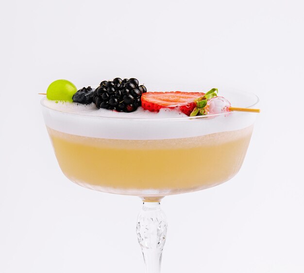 Close up Yellow Cocktail with white foam with berries