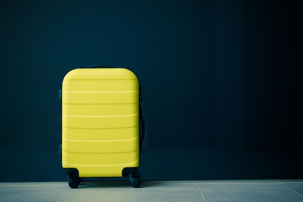 Photo close-up of yellow trolley bag against blue wall indoors