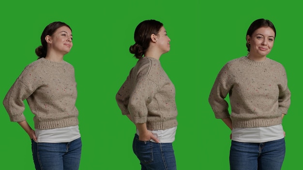 Close up of young adult posing over green screen backdrop, standing on greenscreen isolated template. Female model looking natural and confident, acting optimistic and smiling on camera.