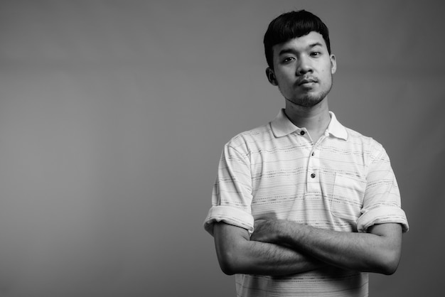 Close up of young Asian man wearing striped polo shirt