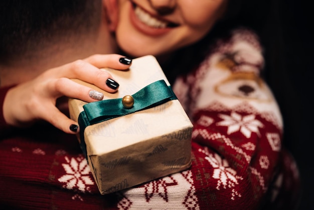 Close up of young beautiful woman hugging man holding christmas present family tradition exchange