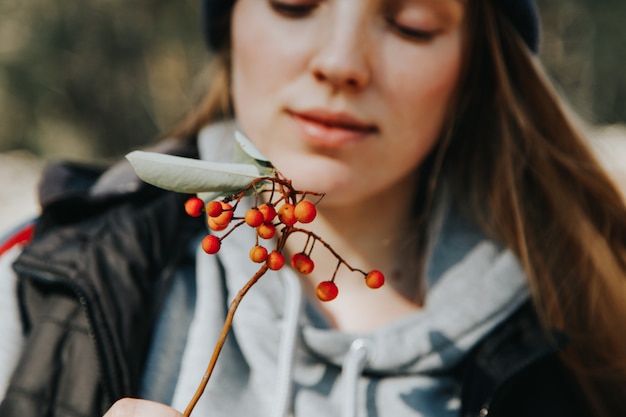 Close-up of a Young caucasian girl holding a twig with wild berries in her hands. Trekking in the forest concept.