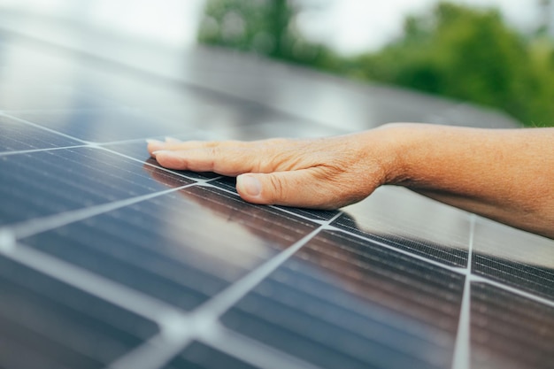 Close up of an young engineer hand is checking an operation of sun and cleanliness of photovoltaic solar panels on a sunset Conceptrenewable energy technologyelectricityservice greenfuture