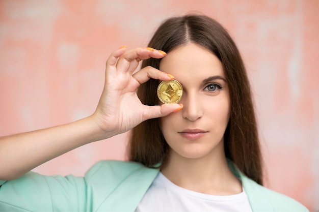 Close up young female is holding cryptocurrency in front eye Online virtual future currency concept