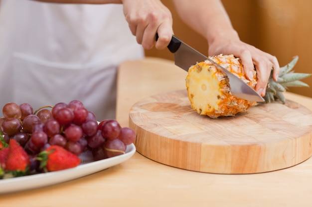 Close up of young feminine hands slicing a pineapple