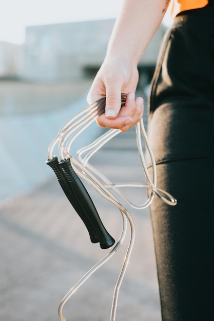 Close up of young hand holding a jump rope training outside Preparing herself for coaching Cardio exercises intense and daily routine Tone and stretch the body with rest blocks Banner workout