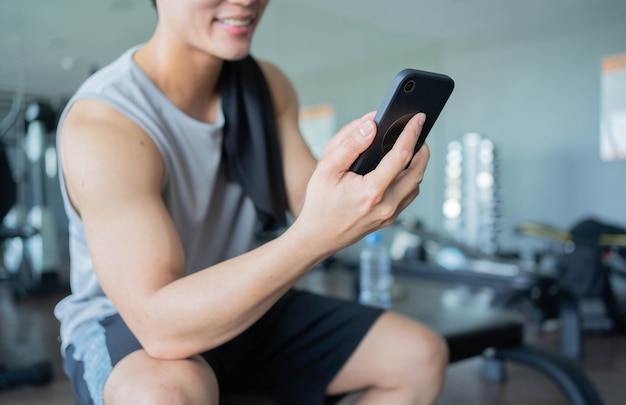 close up young man hand use smartphone while rest at gym for technology and lifestyle concept