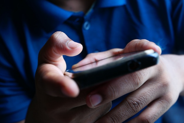 Close up of young man hand using smart phone.