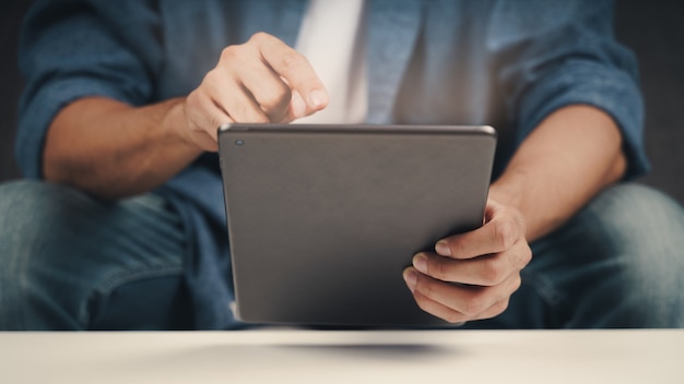 Close up of young man using tablet on the sofa. searching, browsing, shoping online, social network.