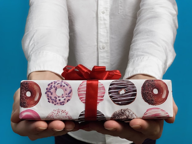 Close up of young man in a white shirt gives gift