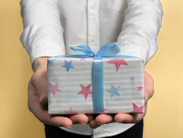 Close up of young man in a white shirt gives gift