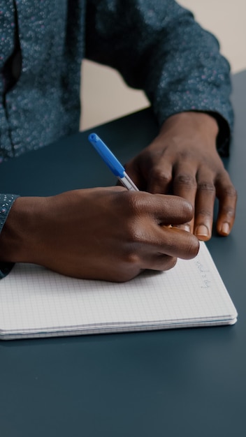 Close up of young person taking notes on notepad using a pen