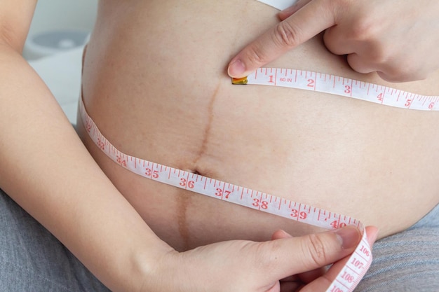 Close up of Young pregnant woman measuring her belly