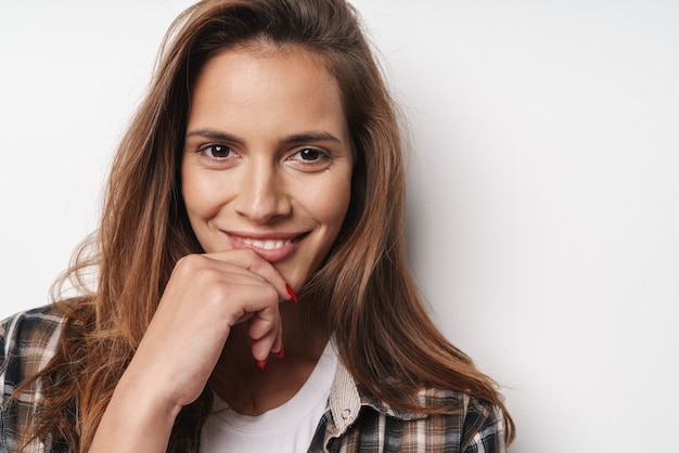 Close up of a young smiling beautiful girl wearing plaid shirt standing isolated over white wall, posing