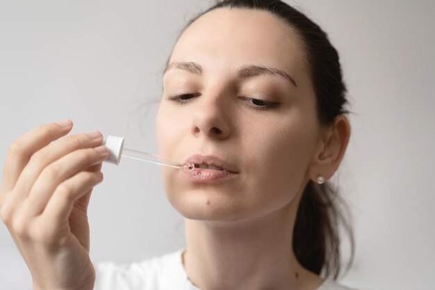 Photo close-up of young woman applying make-up against wall