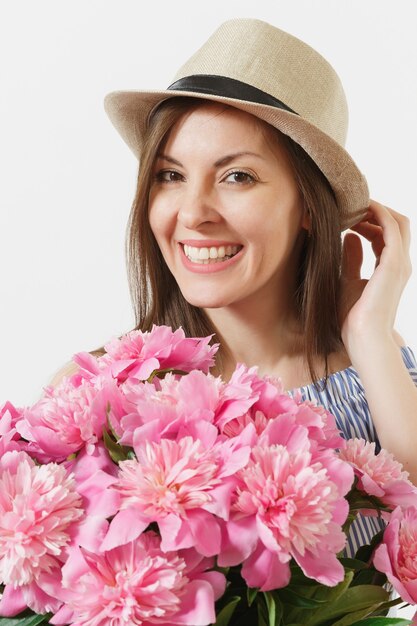 Close up of young woman in dress, hat holding bouquet of beautiful pink peonies flowers isolated on white background. St. Valentine's Day, International Women's Day holiday concept. Advertising area.