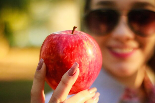 Photo close-up of young woman holding apple