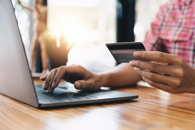 Close up young woman holding credit card and using laptop computer for online shopping Online payment shopping concept