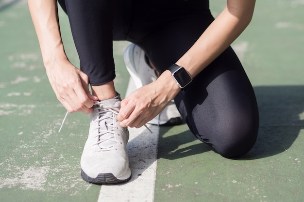 Close up of young woman lace up her shoe ready to workout on exercising in the park