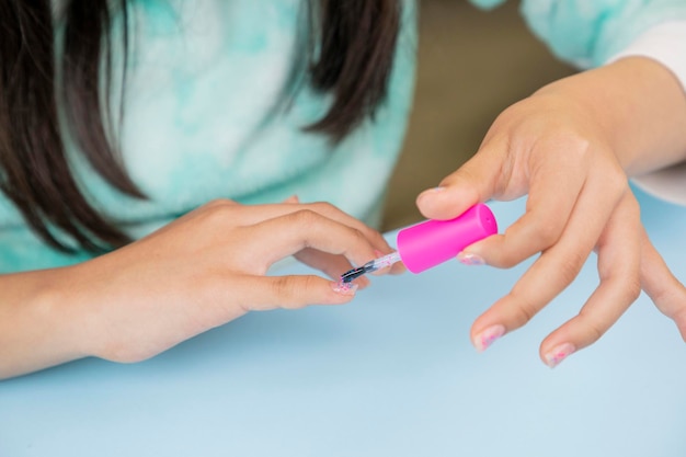 Close up of young woman's hands painting her nails with a varnish and copy space