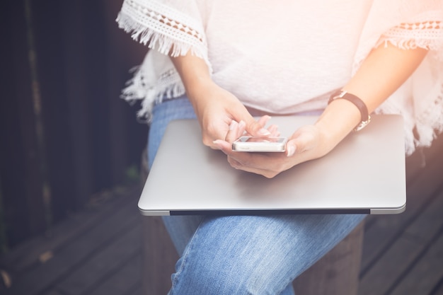 Close up young woman using mobile phone and laptop