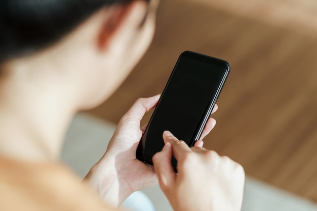 Close up of young woman using smartphone on the sofa. searching, browsing, shoping online, social network.