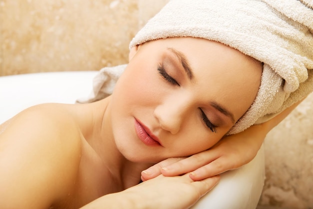 Close-up of young woman with eyes closed lying in bathtub at home