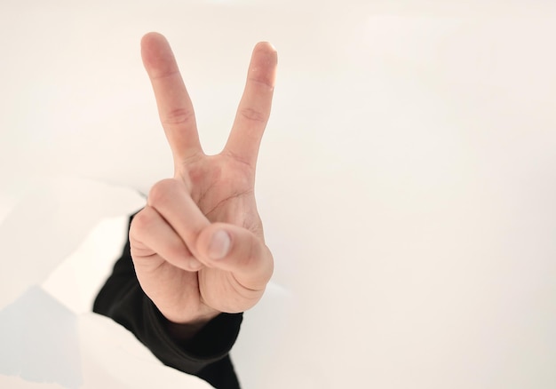 Close upbusinessman showing his index finger through the torn paperphoto with copy space