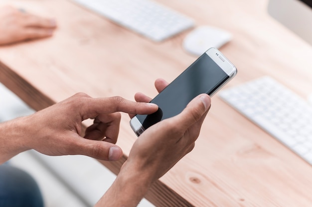 Close upclose up. businessman uses his smartphone in the workplace. people and technology