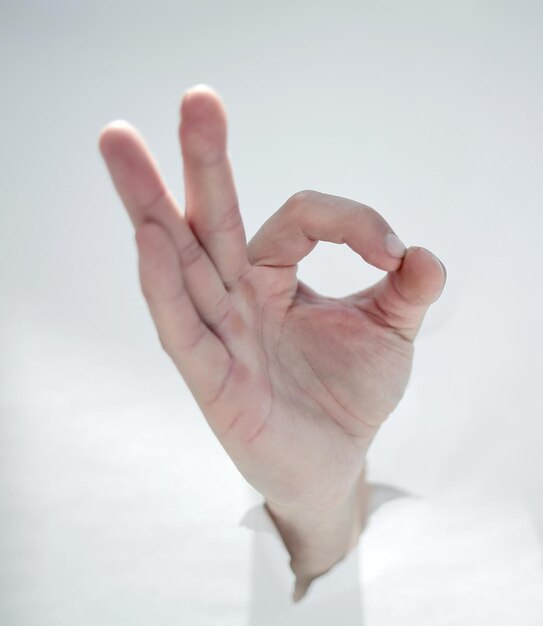 Close upmale hand breaking through the paper wall and showing OK photo with copy space