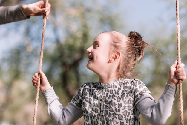 Close uppretty girl sitting on a swing in the garden