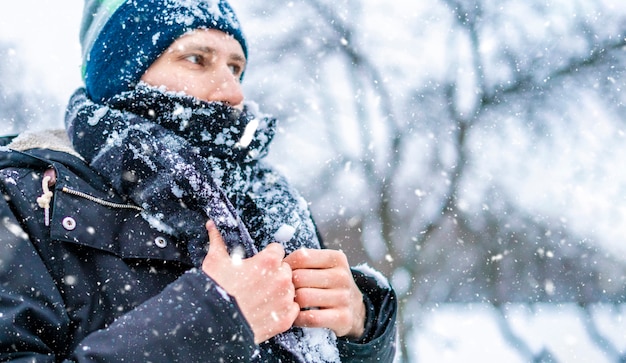 Close uprost man'sace with scarf covered by snow on a winter day