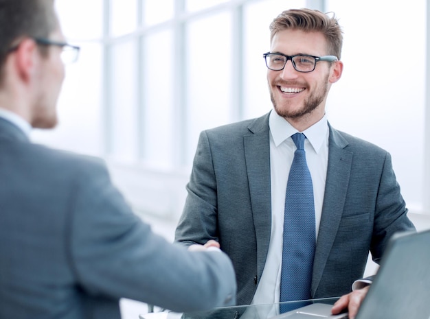 Close upsmiling business people shaking hands in office