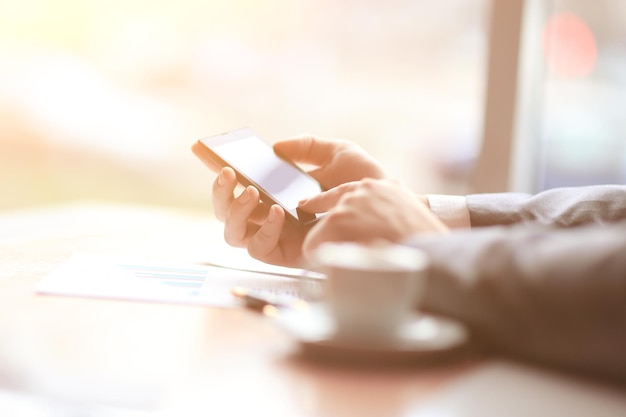 Close upthe businessman uses a smartphone sitting at his Desk