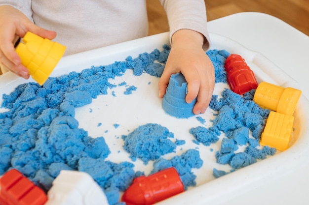 Close view of child's hands playing with kinetic sand. Children's creative game for early development and fine motor skills.